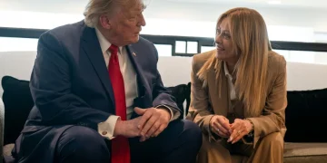 Donald Trump e Giorgia Meloni siedono sorridendo, conversano animatamente sul divano.