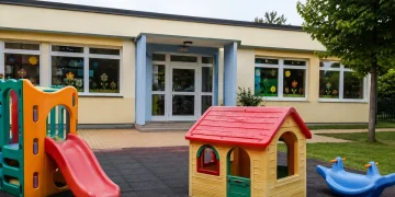 Esterno di un asilo con scivolo, casetta colorata e altri giochi per bambini