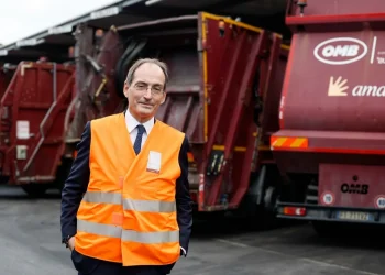 Alessandro Filippi in gilet arancione posa davanti camion Ama