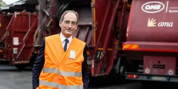 Alessandro Filippi in gilet arancione posa davanti camion Ama