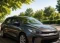 Berlina grigia parcheggiata su strada alberata sotto il sole estivo