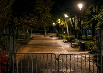 Cancello metallico chiuso impedisce accesso a parco pubblico di notte.
