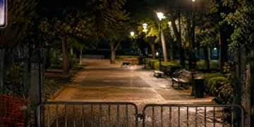 Cancello metallico chiuso impedisce accesso a parco pubblico di notte.