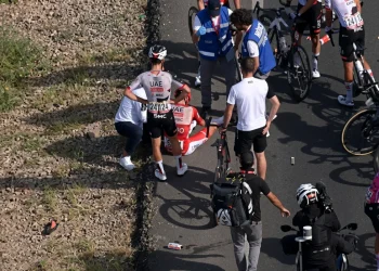 Ciclista Tadej Pogačar seduto a terra dopo caduta alla Vuelta.