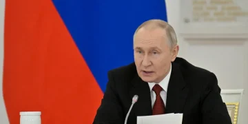 Vladimir Putin in giacca e cravatta parla al microfono
