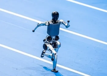Robot bipede nero e grigio corre su pista atletica blu