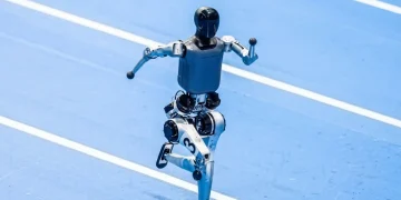 Robot bipede nero e grigio corre su pista atletica blu