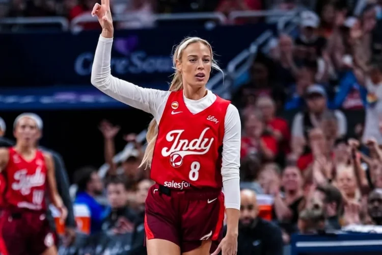 Giocatrice WNBA con maglia numero 8 e due dita alzate in campo.