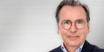 Ritratto di Carlos Tavares, CEO di Stellantis, sorride con occhiali.