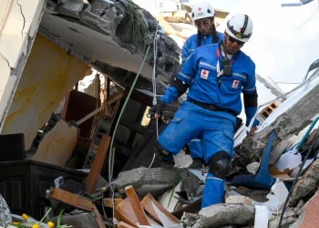 Soccorritori della Croce Rossa camminano tra le macerie di un edificio crollato