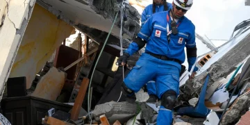 Soccorritori della Croce Rossa camminano tra le macerie di un edificio crollato