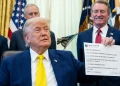 Donald Trump con giacca blu e cravatta gialla in un ufficio.