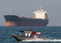 Motovedetta iraniana pattuglia nave mercantile con soldati armati e bandiera.
