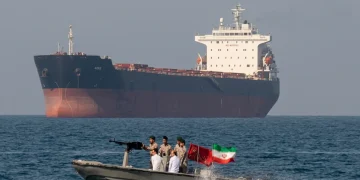Motovedetta iraniana pattuglia nave mercantile con soldati armati e bandiera.