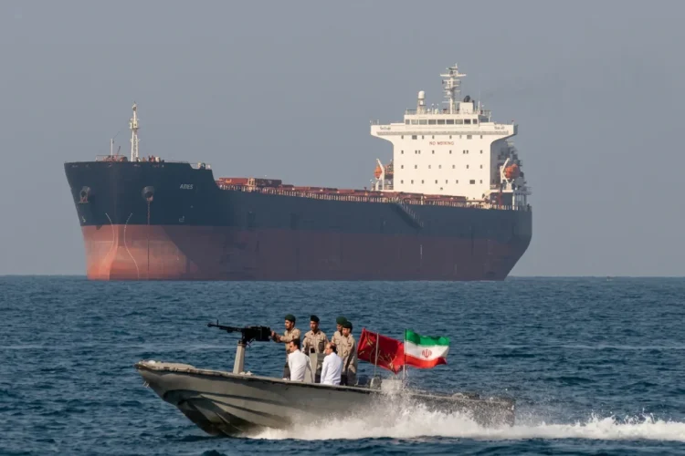 Motovedetta iraniana pattuglia nave mercantile con soldati armati e bandiera.