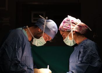 Focused surgeons performing surgery under dramatic lighting in a hospital operating room.