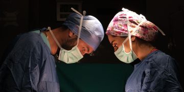 Focused surgeons performing surgery under dramatic lighting in a hospital operating room.