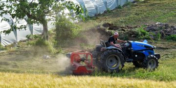 A man driving a tractor in a field near Rizza, Veneto, Italy.