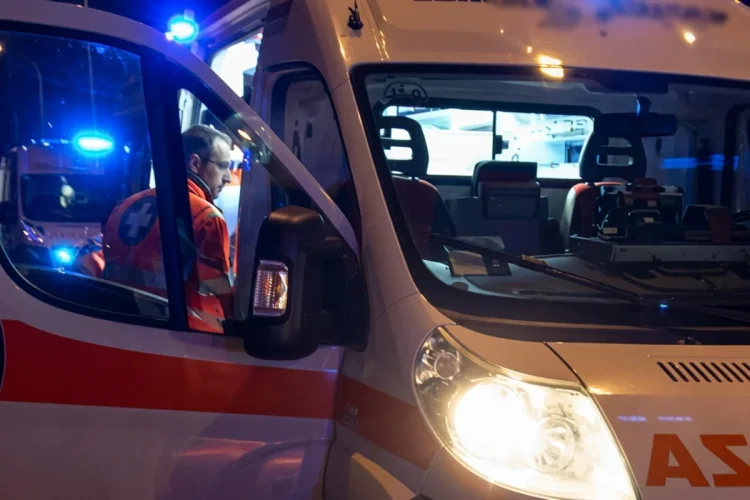 Soccorritore all'interno di un'ambulanza con luci blu accese di notte.