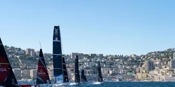 Barche a vela America's Cup sfrecciano in mare davanti alla costa di Napoli.