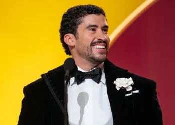Uomo sorridente con smoking nero tiene in mano un premio Grammy