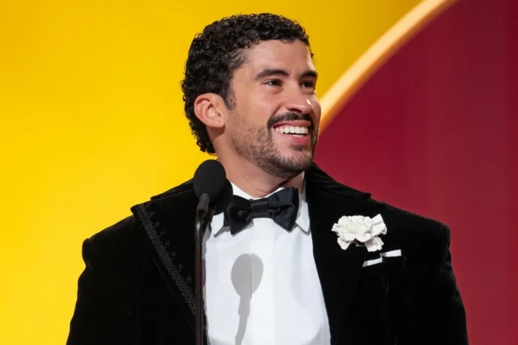 Uomo sorridente con smoking nero tiene in mano un premio Grammy