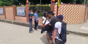 Studenti sfocati in strada vicino a un muro colorato e un cartello. Sparatoria in una scuola nelle Filippine: almeno un morto, quattro feriti