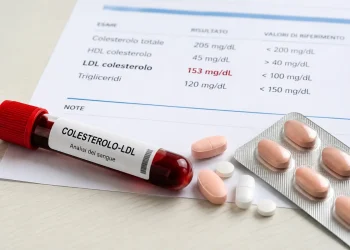 Provetta con sangue, referto medico e farmaci per colesterolo alto