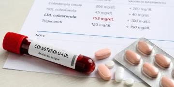 Provetta con sangue, referto medico e farmaci per colesterolo alto