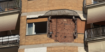 Facciata di un edificio danneggiato con intonaco crollato, mattoni a vista. Roma, esplosione fa crollare parte di un muro durante la disinfestazione di un nido di vespe