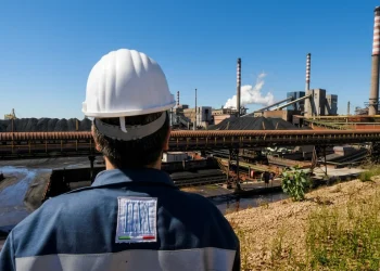 Operaio ILVA osserva lo stabilimento siderurgico di Taranto