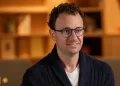 Dario Amodei, CEO di Anthropic, indossa occhiali e cardigan blu.