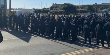 Folla vestita di nero con volti coperti su una strada a Dover.