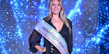 Una giovane donna sorride con fascia "Miss Italia 2026" e corona. Miss Italia 2026 è Sarah Rizea, la 18enne nuotatrice azzurra delle Fiamme Oro