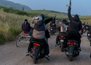 Uomini su moto in campagna, alcuni sollevano fucili e pistole. Catania, kalashnikov alla corsa clandestina di cavalli: arrestato un giovane