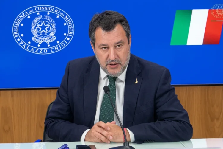 Matteo Salvini parla al microfono con sfondo Palazzo Chigi e bandiera italiana.