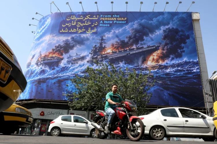 Iranians drive next to an anti-US billboard