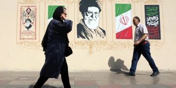 Iranians walk next to wall art