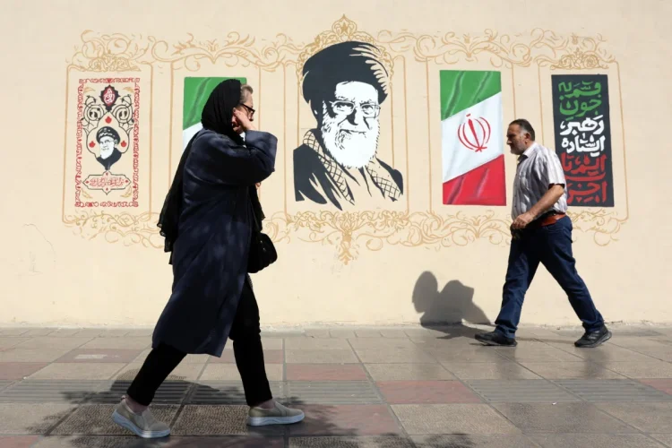 Iranians walk next to wall art