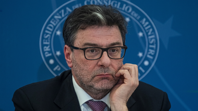 Giancarlo Giorgetti con gli occhiali e logo Istat su porta a vetri.