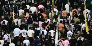 Tifosi della Juventus di spalle in curva allo stadio, alcuni con maglie storiche.