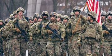 Soldati statunitensi in uniforme mimetica marciano con bandiera americana