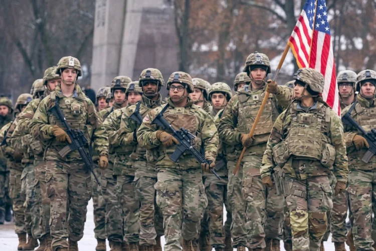 Soldati statunitensi in uniforme mimetica marciano con bandiera americana