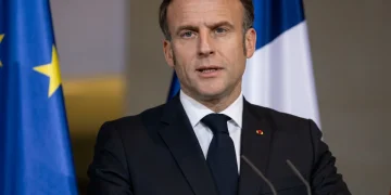 Emmanuel Macron parla davanti bandiera europea e francese.