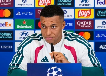 Kylian Mbappé seduto in conferenza stampa con microfono