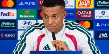Kylian Mbappé seduto in conferenza stampa con microfono