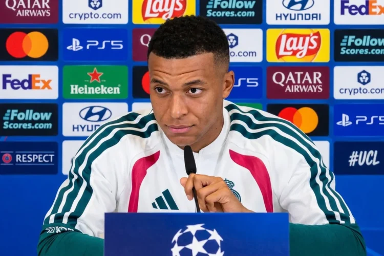 Kylian Mbappé seduto in conferenza stampa con microfono