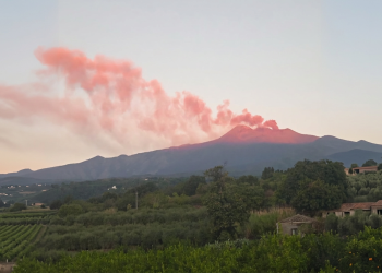 Etna erutta fumo rosato, agricoltura siciliana in primo piano al tramonto. L’Etna emette una nuova nube di cenere, attivato il codice rosso per il traffico aereo