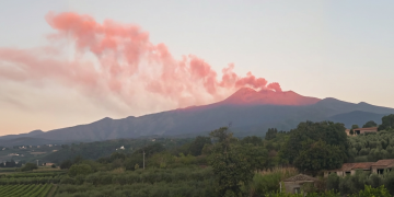 Etna erutta fumo rosato, agricoltura siciliana in primo piano al tramonto. L’Etna emette una nuova nube di cenere, attivato il codice rosso per il traffico aereo