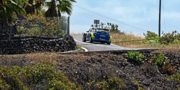 Auto da rally blu percorre curva su strada di montagna